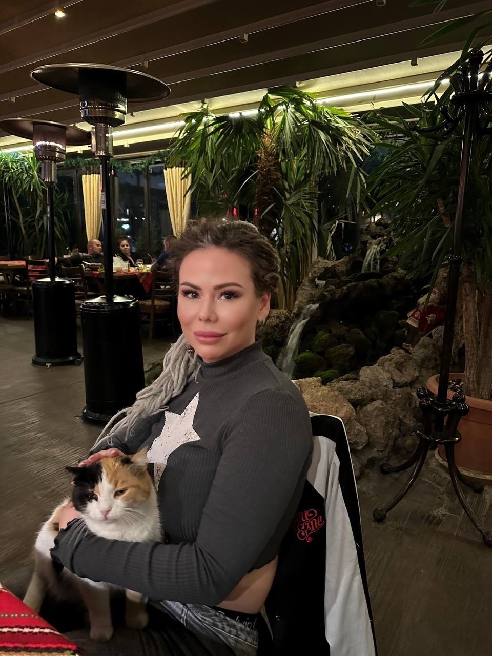 Maria Dyukova (Mariangel777) sitting with a cat in a restaurant