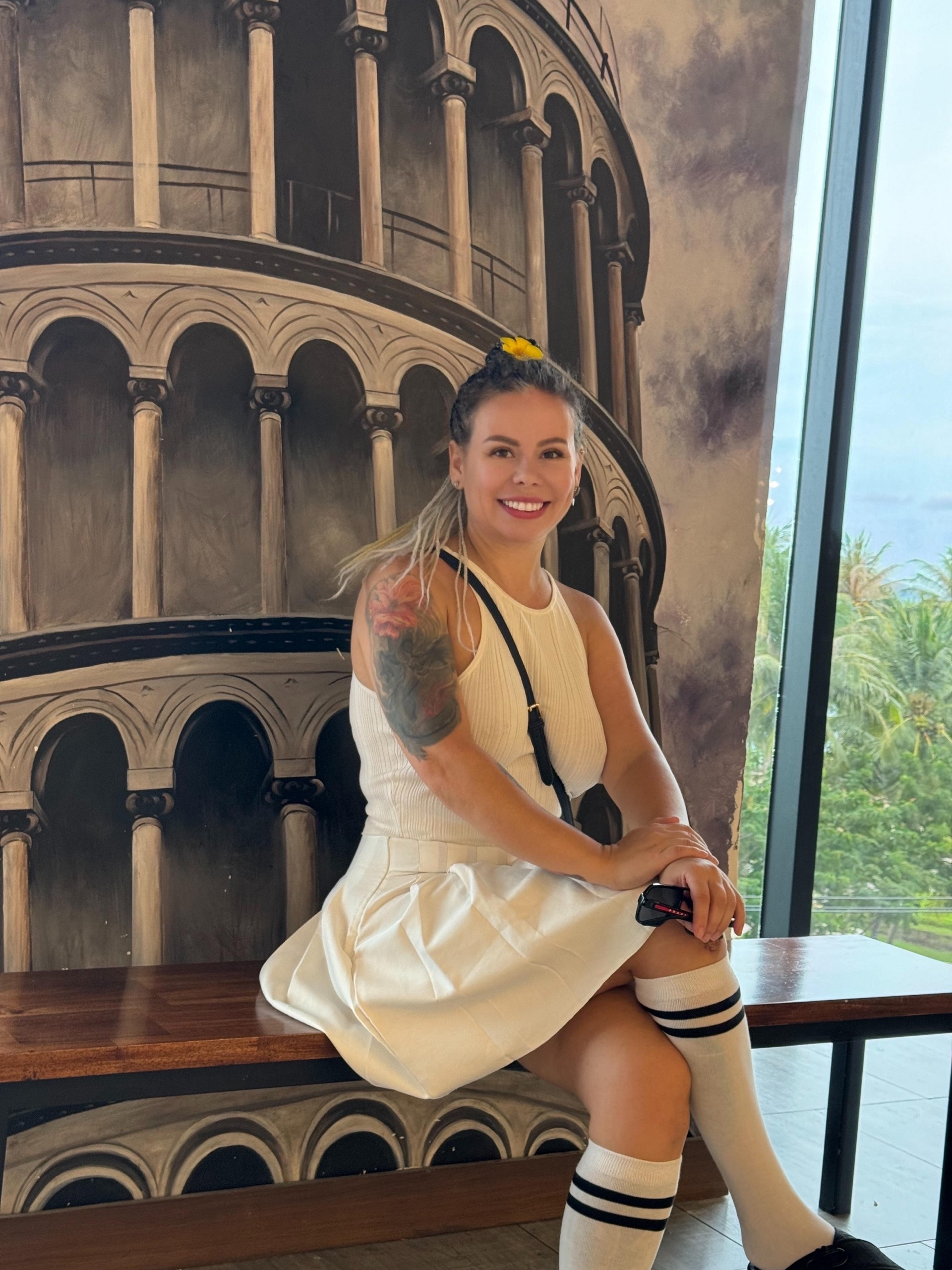 Maria Dyukova (Mariangel777) sitting indoors near a mural of the Leaning Tower of Pisa